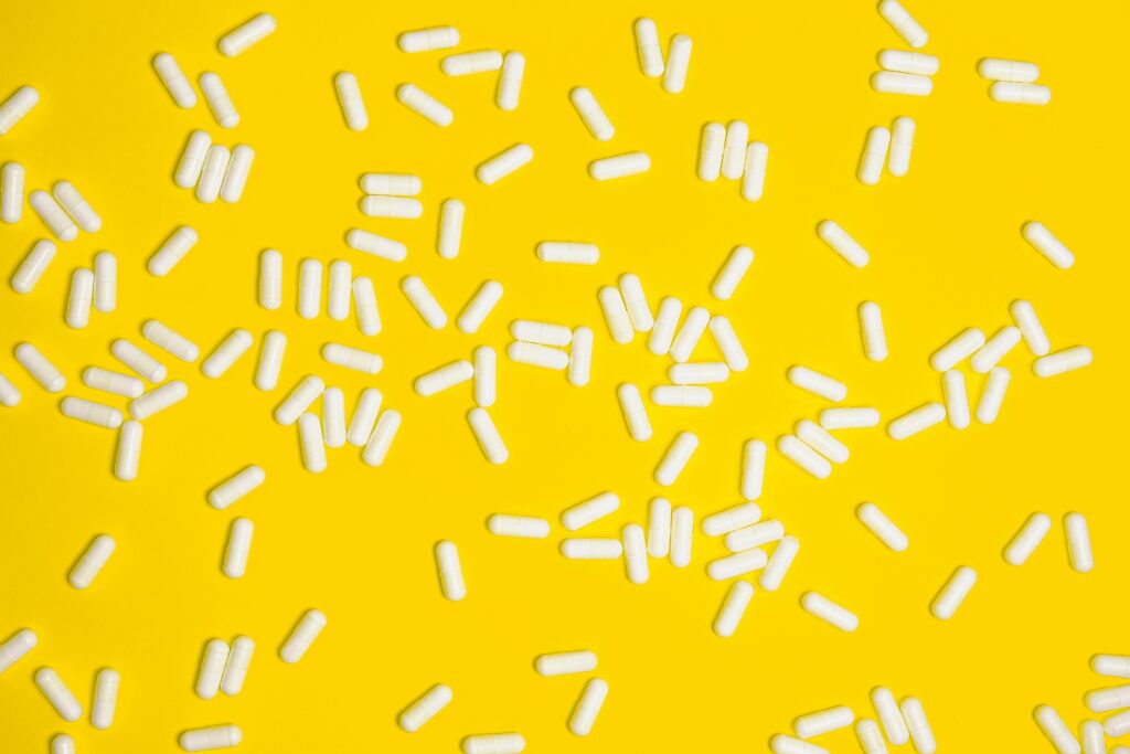 Scattered white pills on a vibrant yellow background, highlighting healthcare and medication themes.